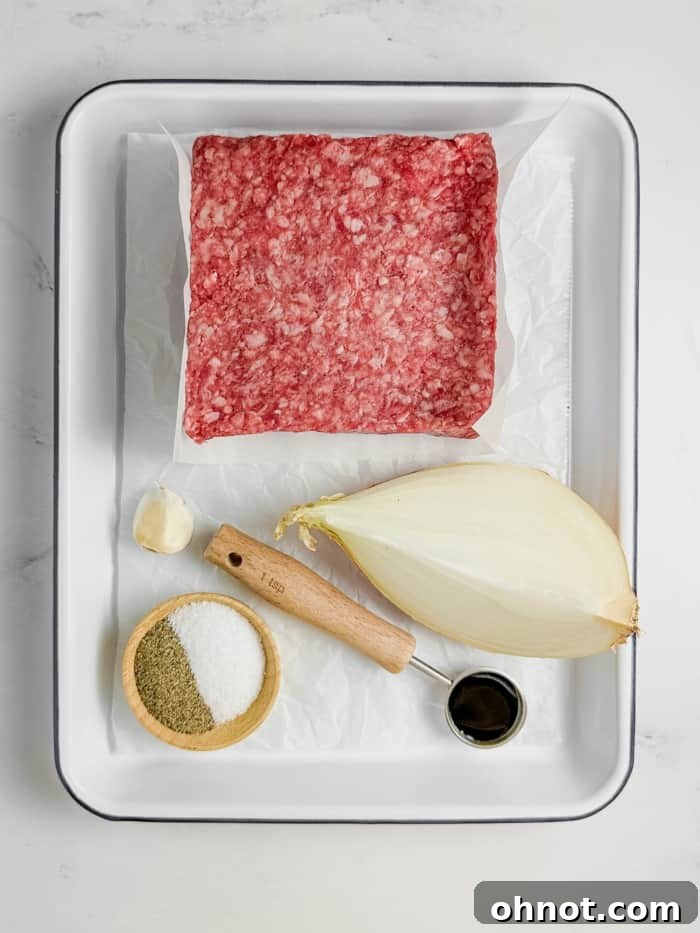 Ingredients for gluten free burgers, including ground beef, onion, garlic, and coconut aminos, laid out on a wooden board.