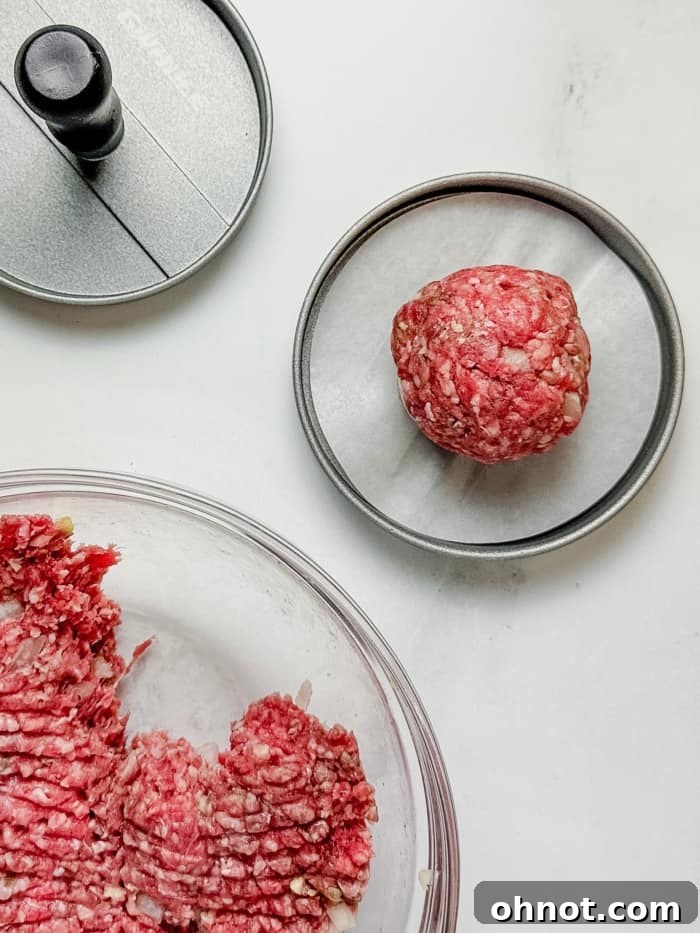 A hand using a burger press to form a patty from the seasoned ground meat mixture.