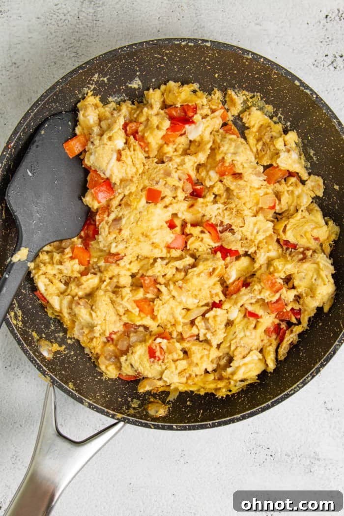 Close-up of scrambled eggs mixed with diced bell peppers in a skillet.