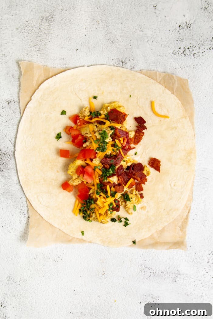 A burrito filling with eggs, bacon, cheese, and vegetables ready for folding.