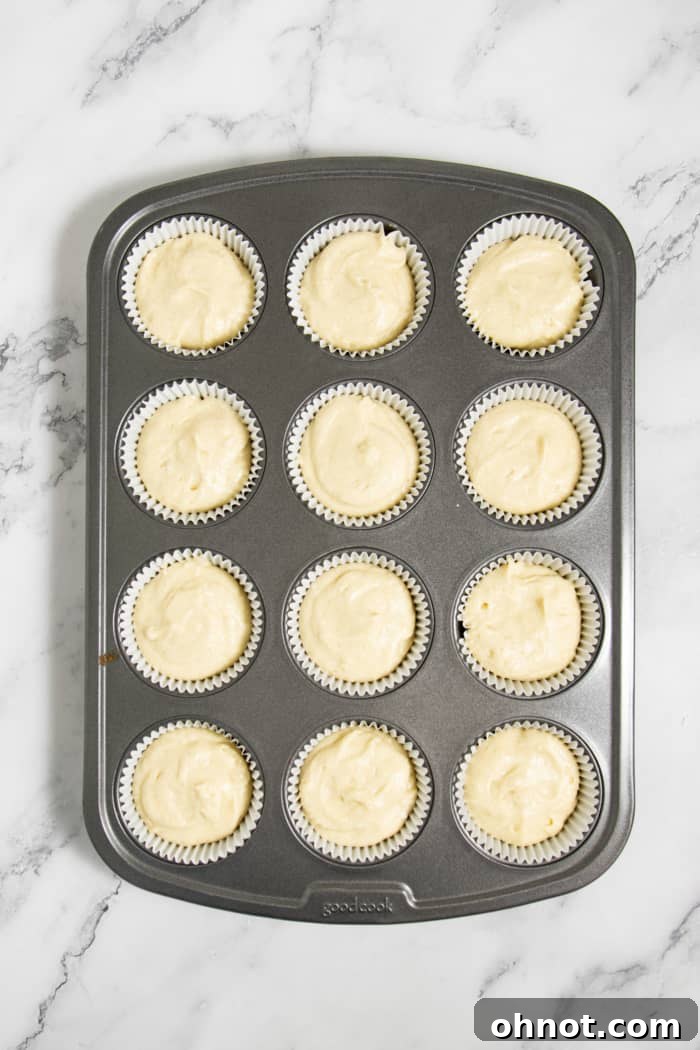 Muffin tin with liners filled with cupcake batter.