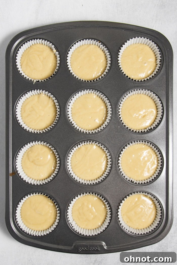 A cupcake pan with liners filled two-thirds with raw batter.