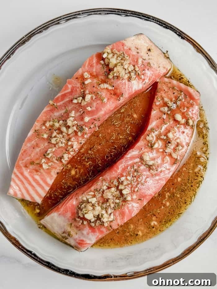 Steelhead trout fillets generously coated in a lemon-herb marinade, ready for baking.