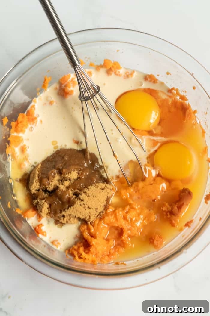 Close-up of eggs, mashed sweet potatoes, and sugar in a mixing bowl.