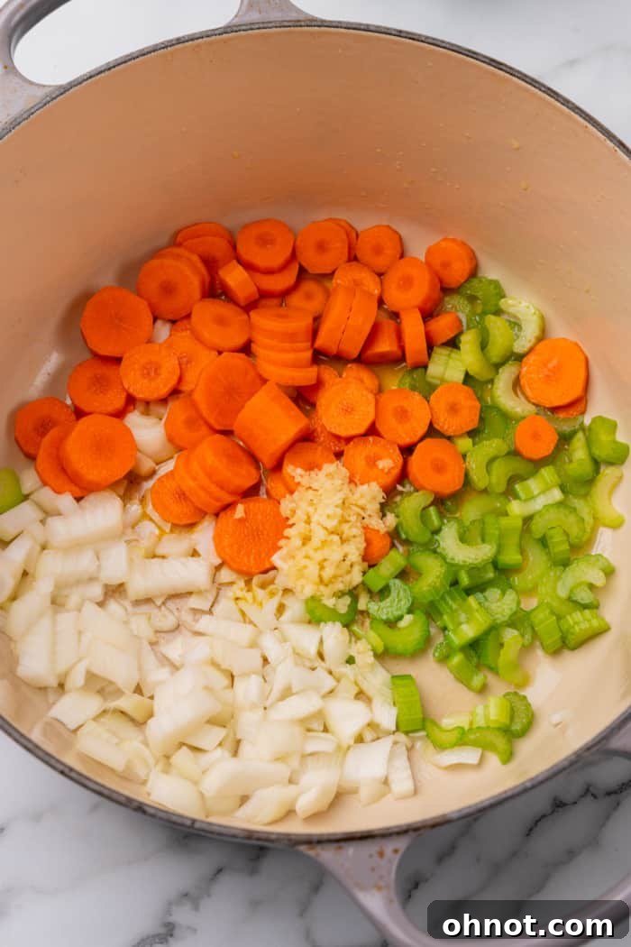Freshly chopped onion, garlic, carrots, and celery simmering in olive oil in a large Dutch oven.