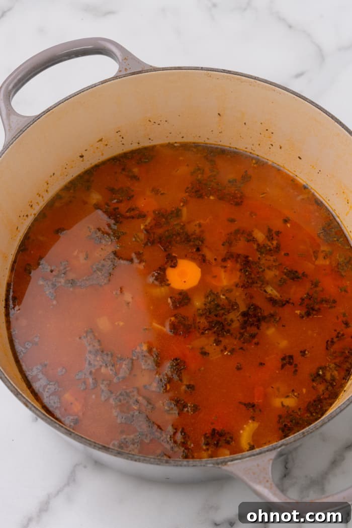 Close-up of broth and carrots simmering gently in a saucepan, infusing with rich flavors.