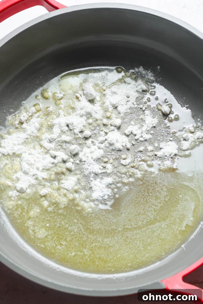 Gluten-free flour being whisked into melted butter in a skillet.