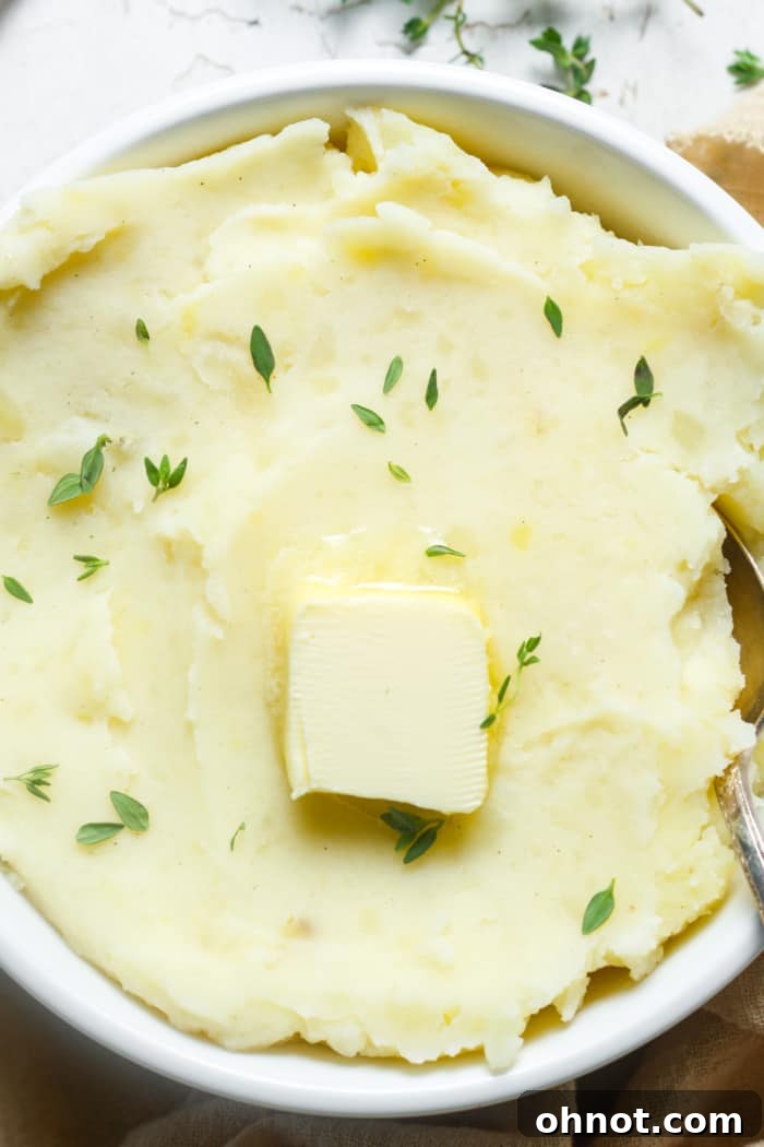 Creamy vegan mashed potatoes in a bowl, garnished with fresh herbs.