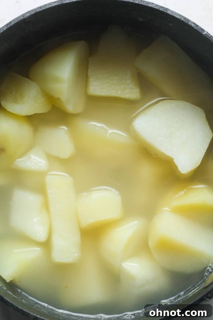 Potato chunks submerged in water in a large saucepan, ready for boiling.