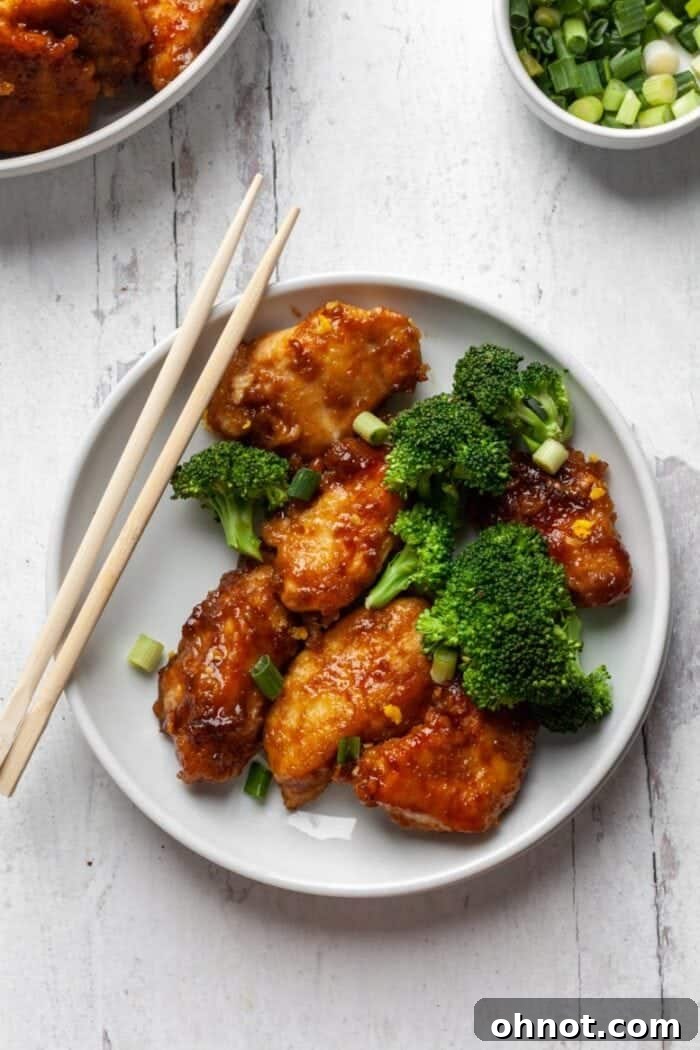 A serving of Whole30 Orange Chicken with cauliflower rice and a sprinkle of green onions, presented in a bowl for a healthy meal.