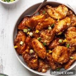 Whole30 Orange Chicken plated, showing tender chicken pieces coated in a vibrant orange sauce, garnished with fresh green onions.