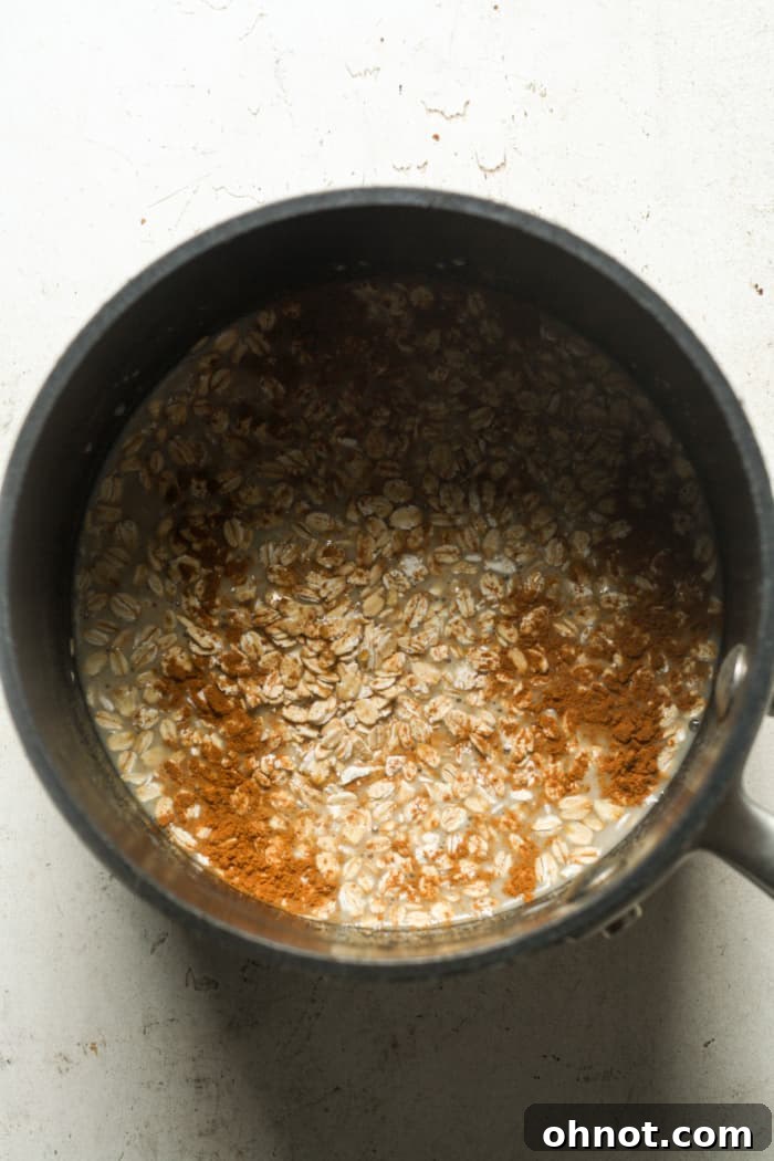 Rolled oats and coconut milk being combined in a saucepan on the stovetop.
