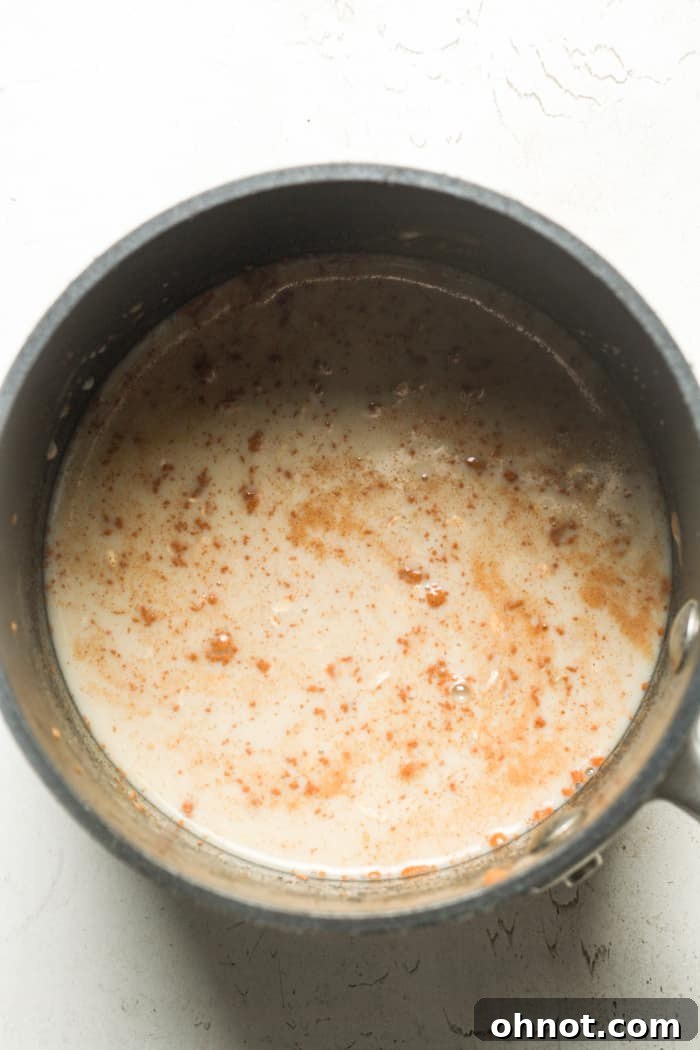 Close-up of coconut milk simmering gently in a saucepan.