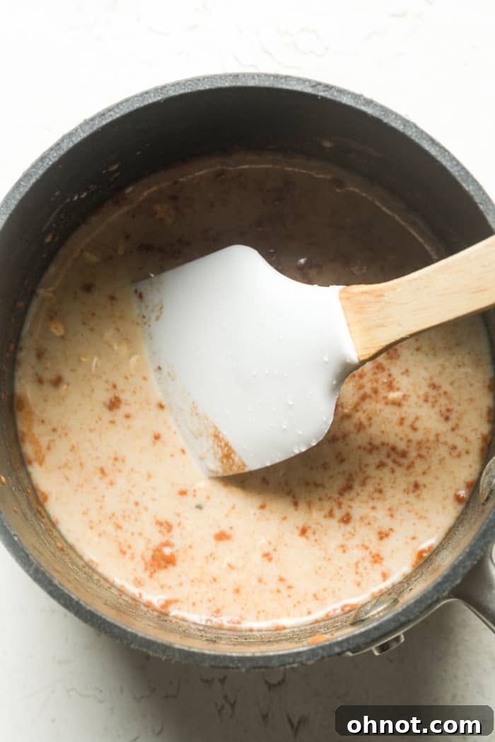 The creamy oatmeal mixture thickening in the saucepan as it cooks, showing its rich texture.