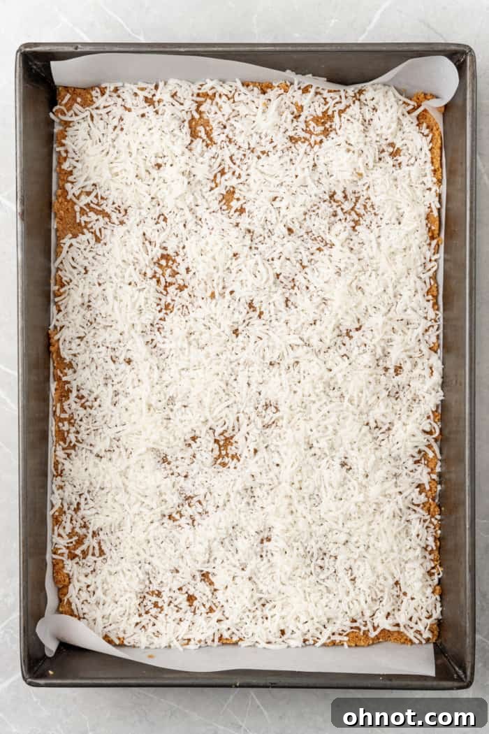 Shredded coconut spread over the crust in a rectangular pan.