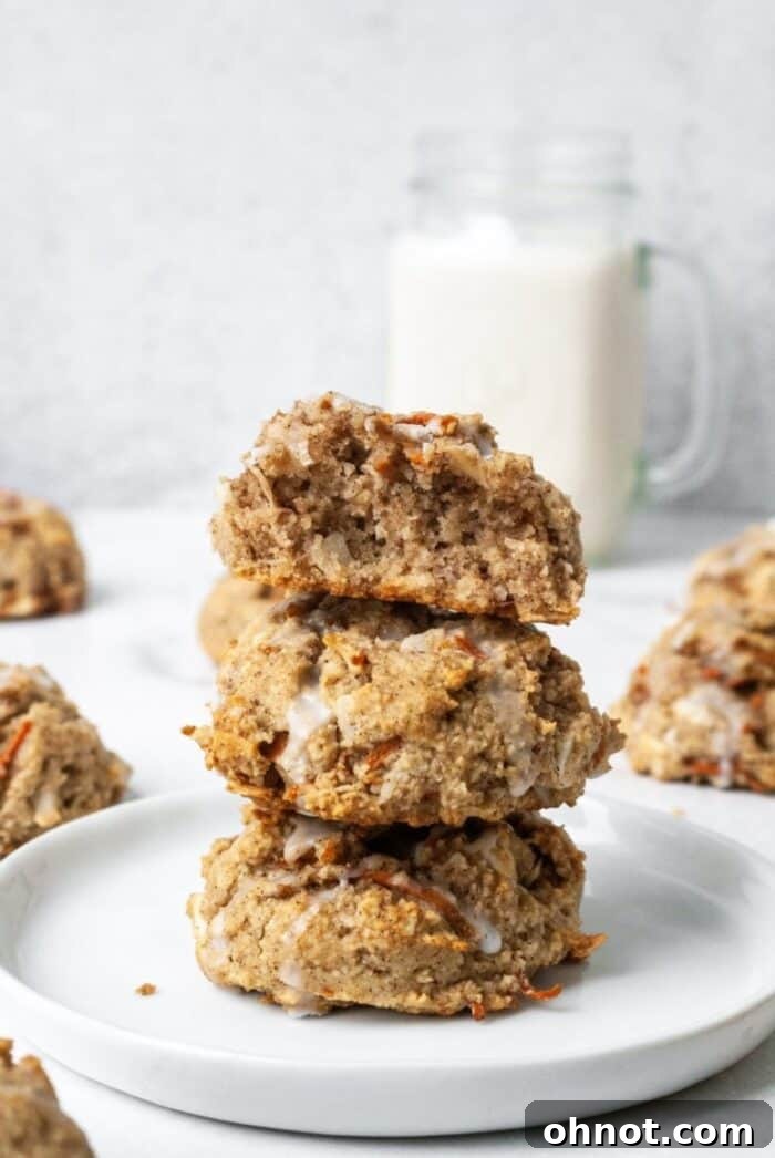 Close-up of three Paleo carrot cake cookies on a white plate, showcasing their soft texture and vibrant speckles of shredded carrot.