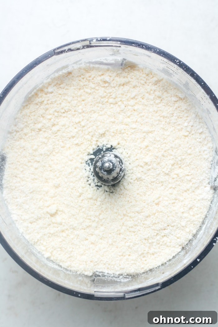 Crumbly mixture of butter and flour in food processor after pulsing.