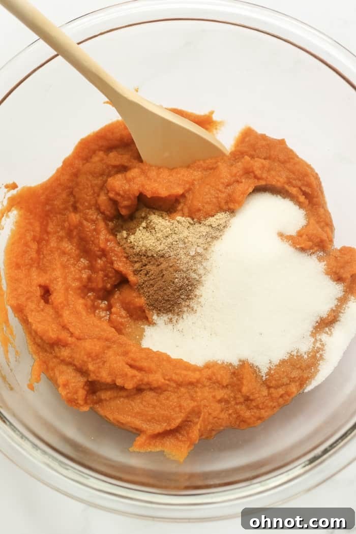 Pumpkin purée and sugar being mixed in a bowl, showing the initial stages of making the healthy pumpkin pie filling.