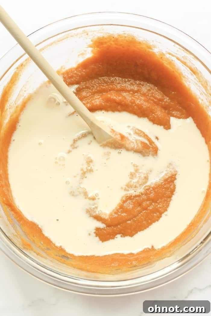 The vibrant orange pumpkin pie filling after adding coconut milk, showing its smooth and creamy consistency.