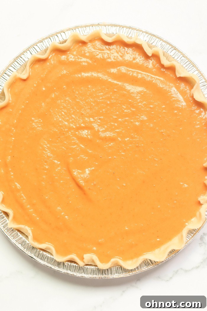 Close-up of the smooth pumpkin batter in a pie crust, ready for baking.