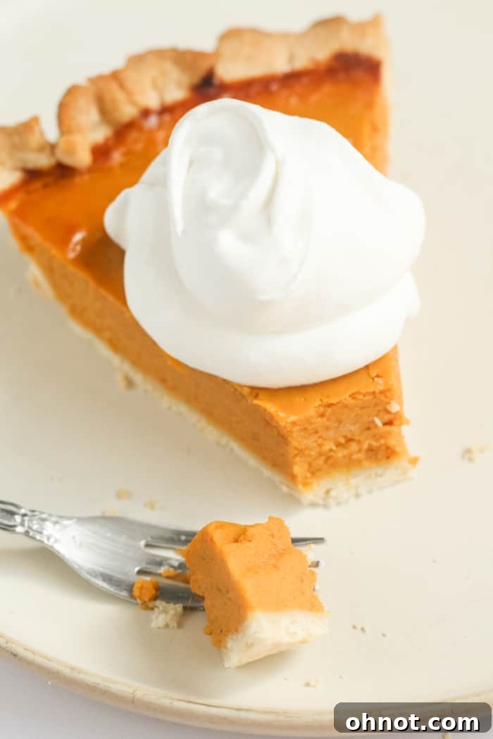 A close-up shot of a healthy pumpkin pie with a bite taken out, highlighting the creamy filling and flaky crust.