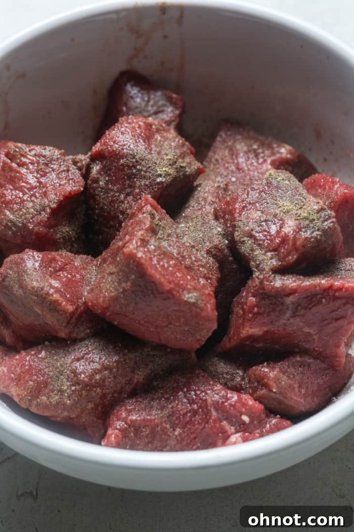Chunks of beef stew meat seasoned and ready for browning.