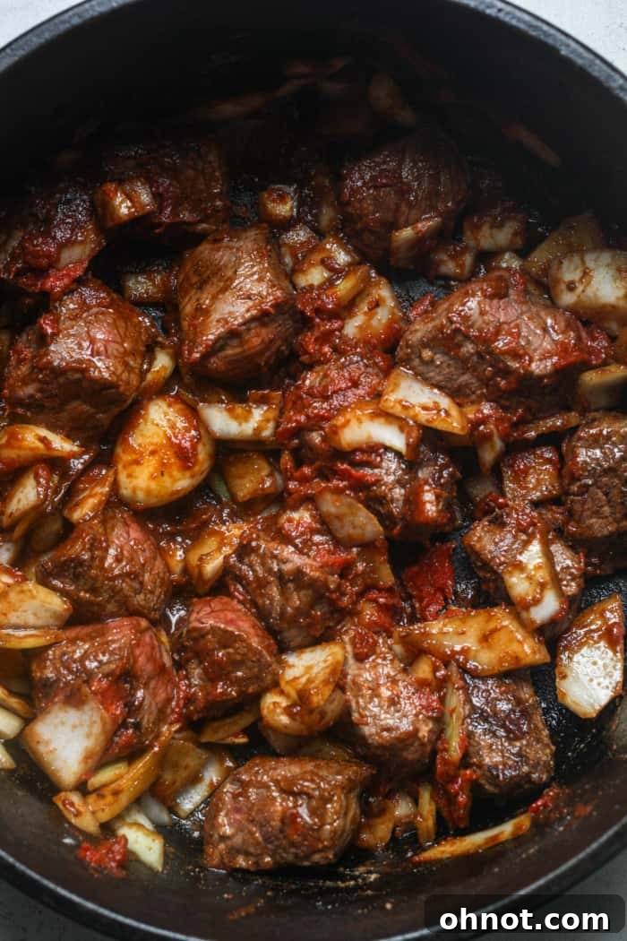 Meat mixed with tomato paste in the Dutch oven.