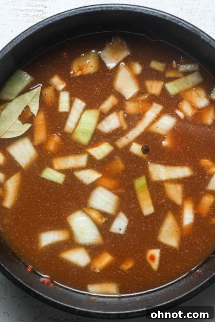 Broth, onions, and bay leaf simmering in the Dutch oven.
