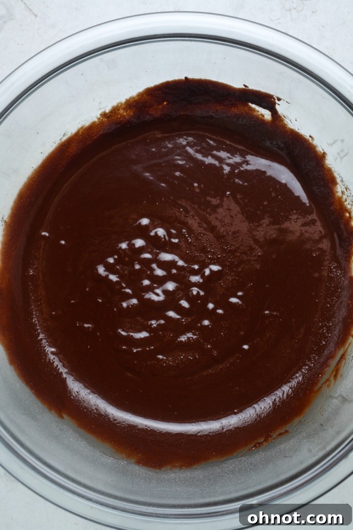 Chocolate batter with added sugar, salt, and vanilla in a glass bowl.