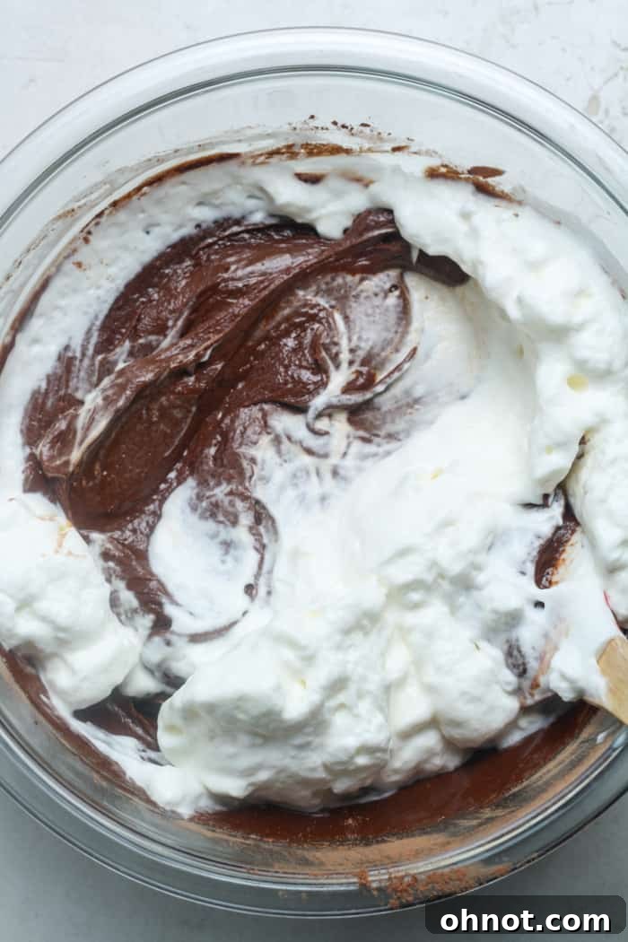 Whipped cream being gently folded into chocolate batter.