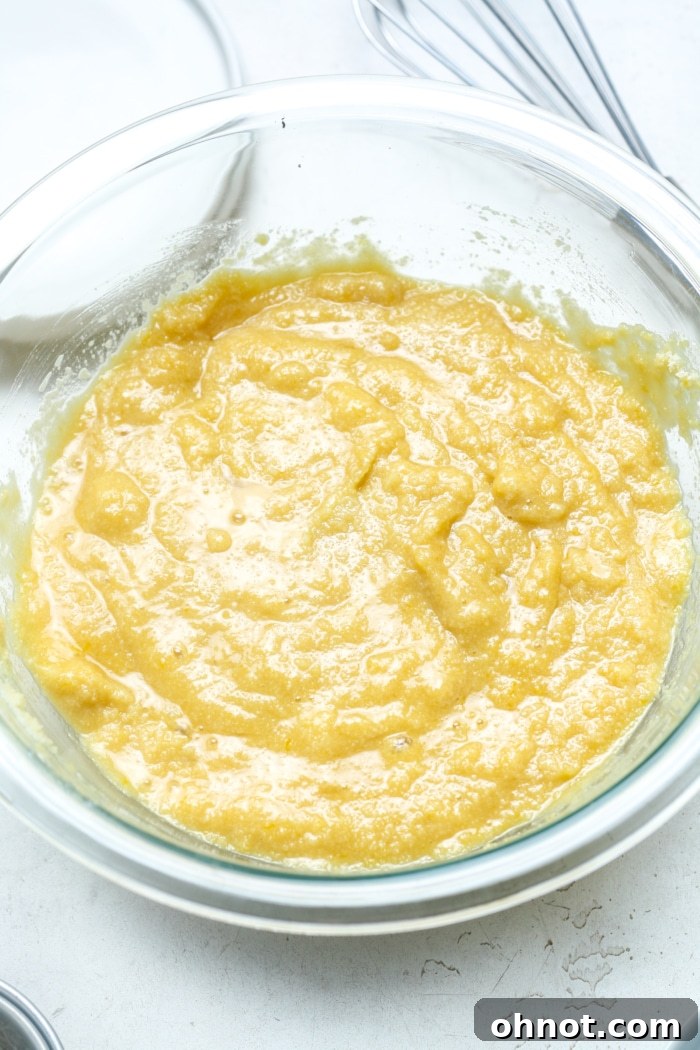 Pale yellow, smooth muffin batter in a mixing bowl after combining wet and dry ingredients, before chocolate chips are added.