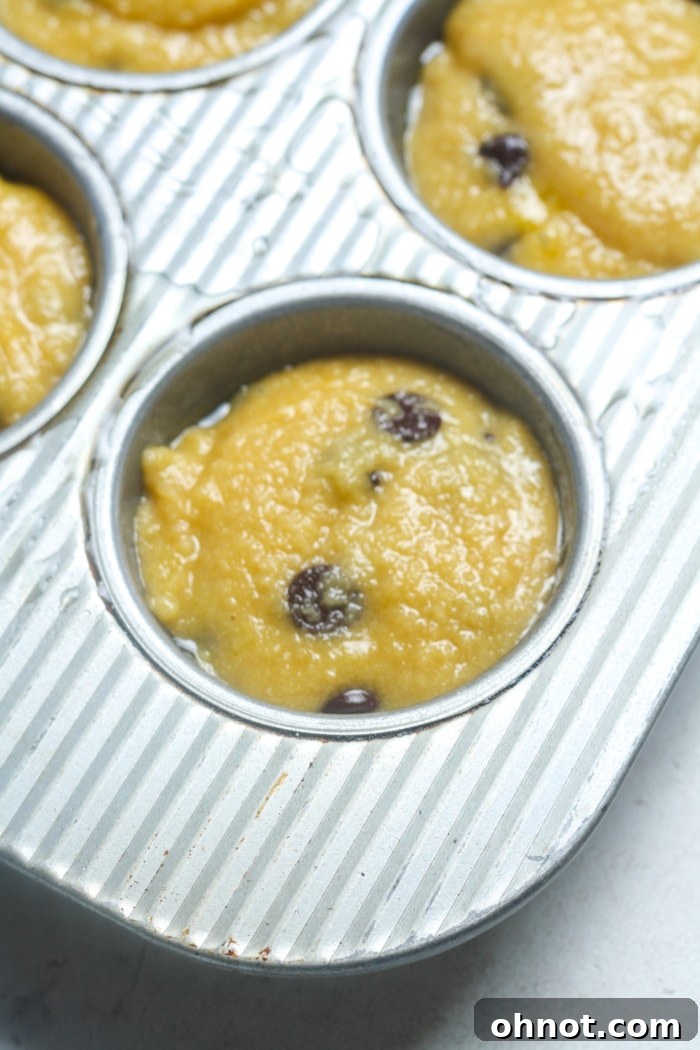 Muffin pan filled with raw chocolate chip muffin batter, evenly portioned and ready for baking.