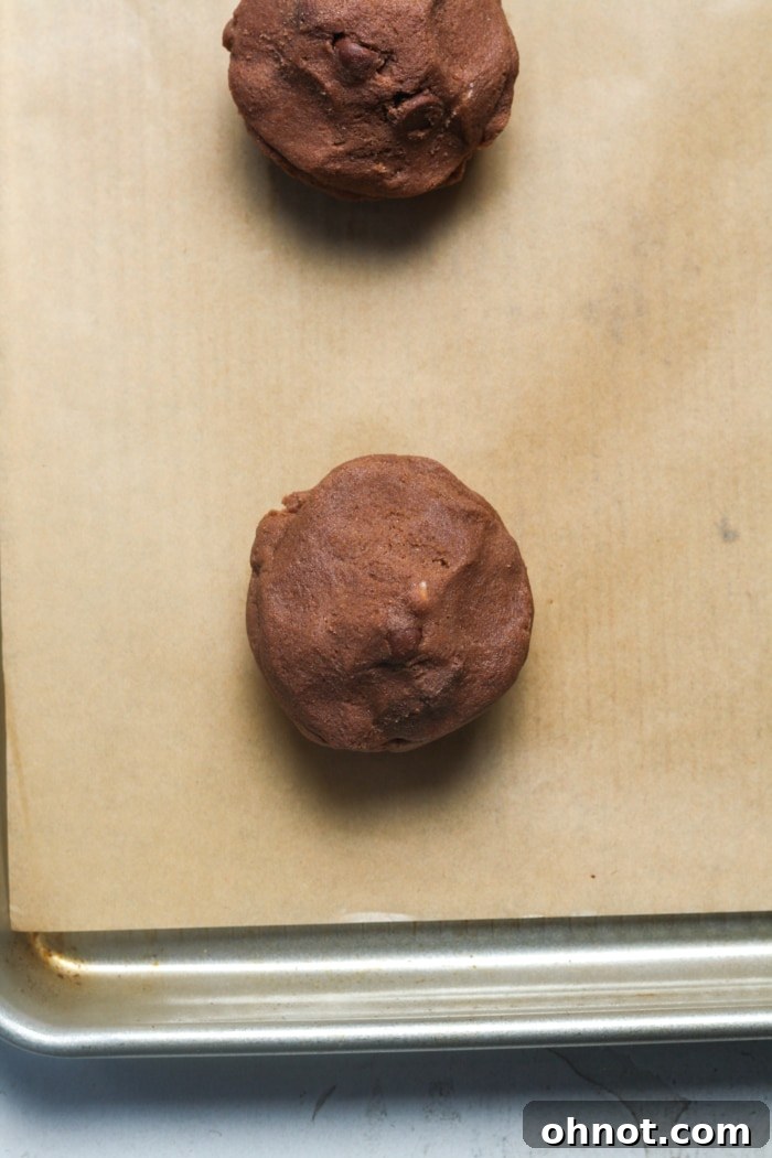 Chocolate cookie dough covering a cheesecake ball, ready for shaping.