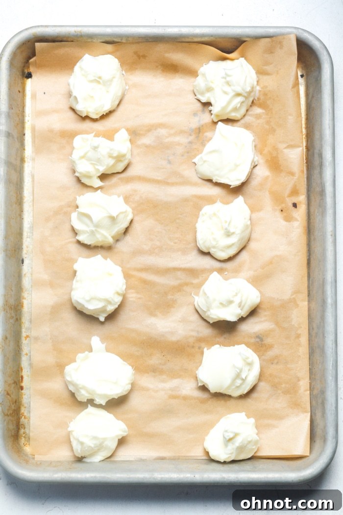 Small balls of vanilla cheesecake filling frozen on a baking sheet.