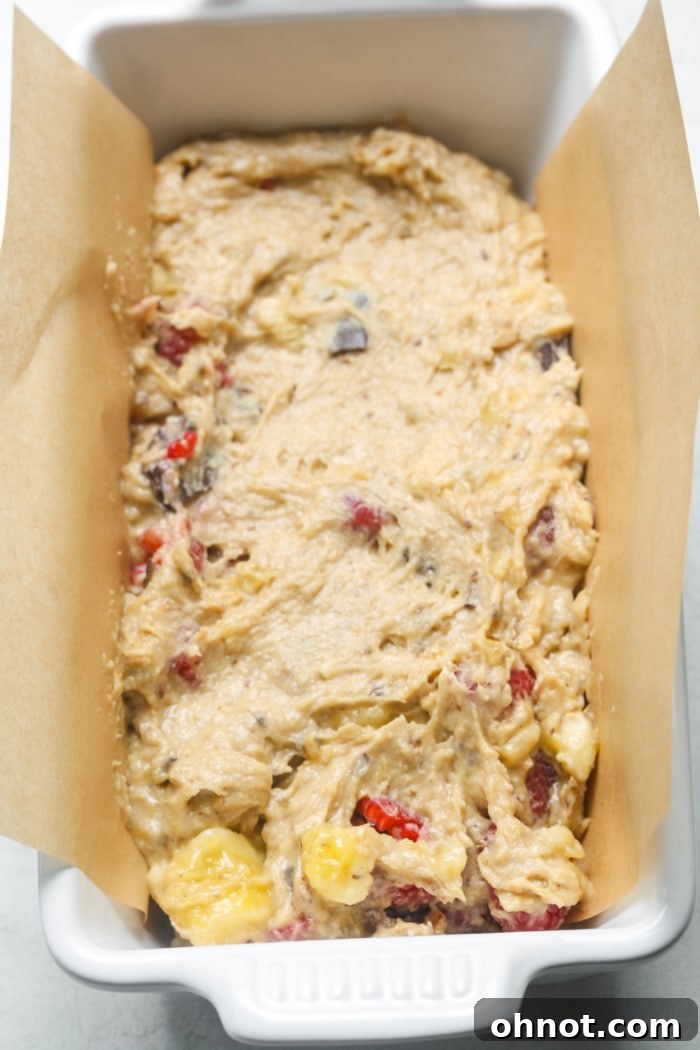 Raspberry and chocolate chip bread batter in a lined loaf pan, ready for baking.
