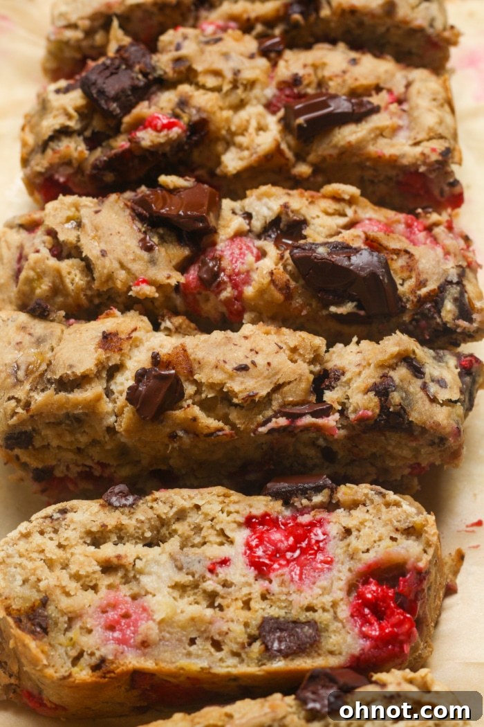 A perfectly sliced loaf of raspberry chocolate chip bread, showing the moist interior and distribution of berries and chocolate.