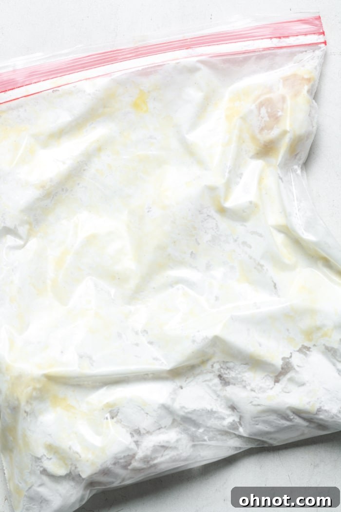 A sealed Ziploc bag containing chicken pieces perfectly coated in the gluten-free flour mixture, ready for cooking.