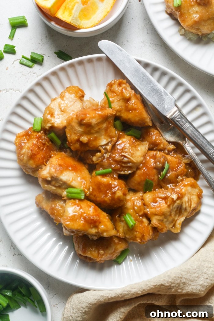 A freshly prepared plate of homemade gluten-free orange chicken, garnished with green onions and ready to be enjoyed.