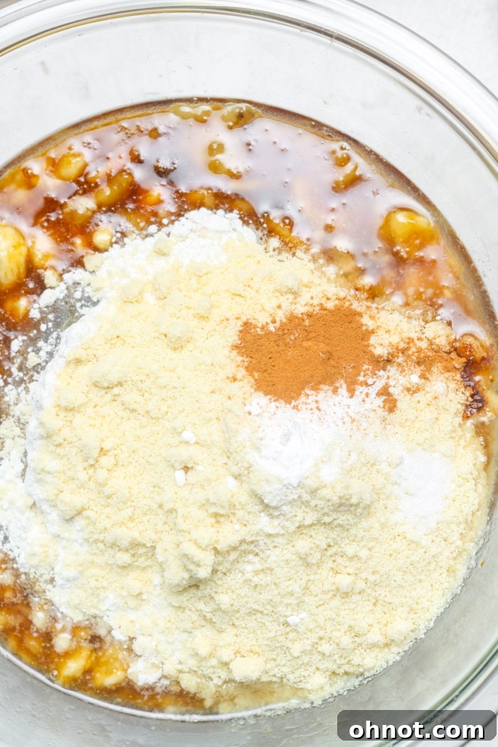 Almond flour and cinnamon being added to the wet ingredients in a bowl.