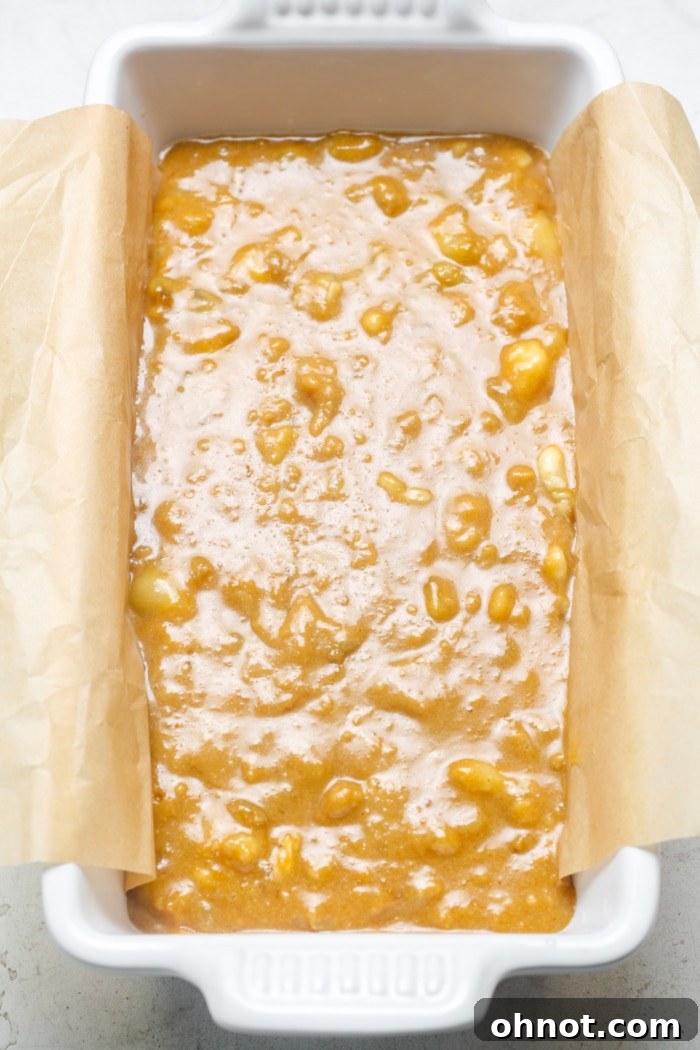 Loaf pan filled with banana bread batter, smoothed into an even layer.