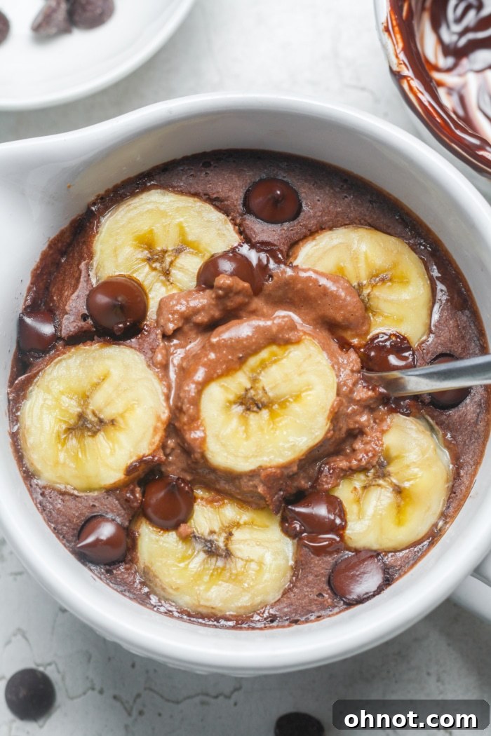 A perfectly baked individual serving of chocolate baked oats, topped with sliced bananas and melted chocolate chips, presented in a rustic oven-safe ramekin.