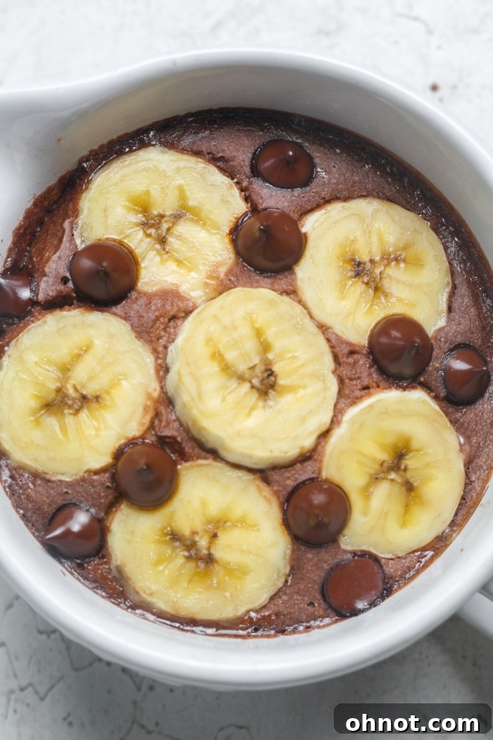 A close-up of a golden-brown, freshly baked chocolate banana oatmeal, still bubbling slightly in an oven-safe ramekin.
