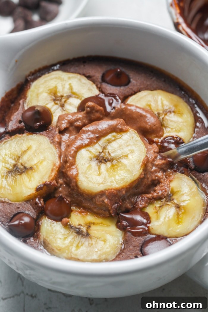 A close-up shot of the interior of baked chocolate oats, showing the gooey melted chocolate chips and soft banana chunks within the moist oat texture.