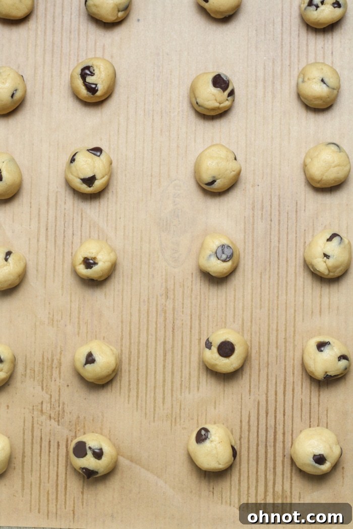 Mini cookie dough balls spaced on a baking sheet.