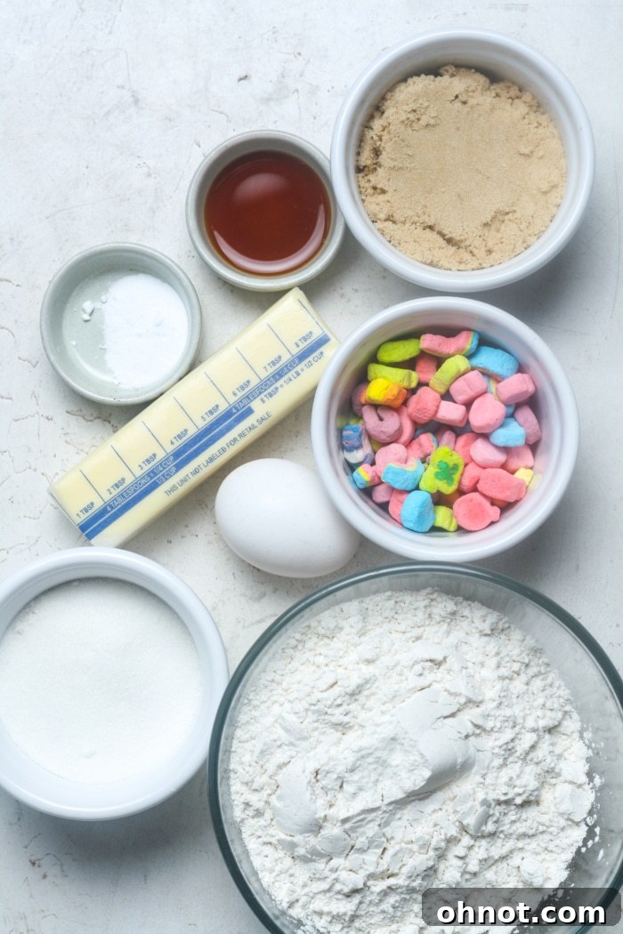 Individual ingredients laid out for making Lucky Charms cookies: butter, sugars, egg, flour, baking soda, salt, vanilla extract, and a bowl of Lucky Charms marshmallows.
