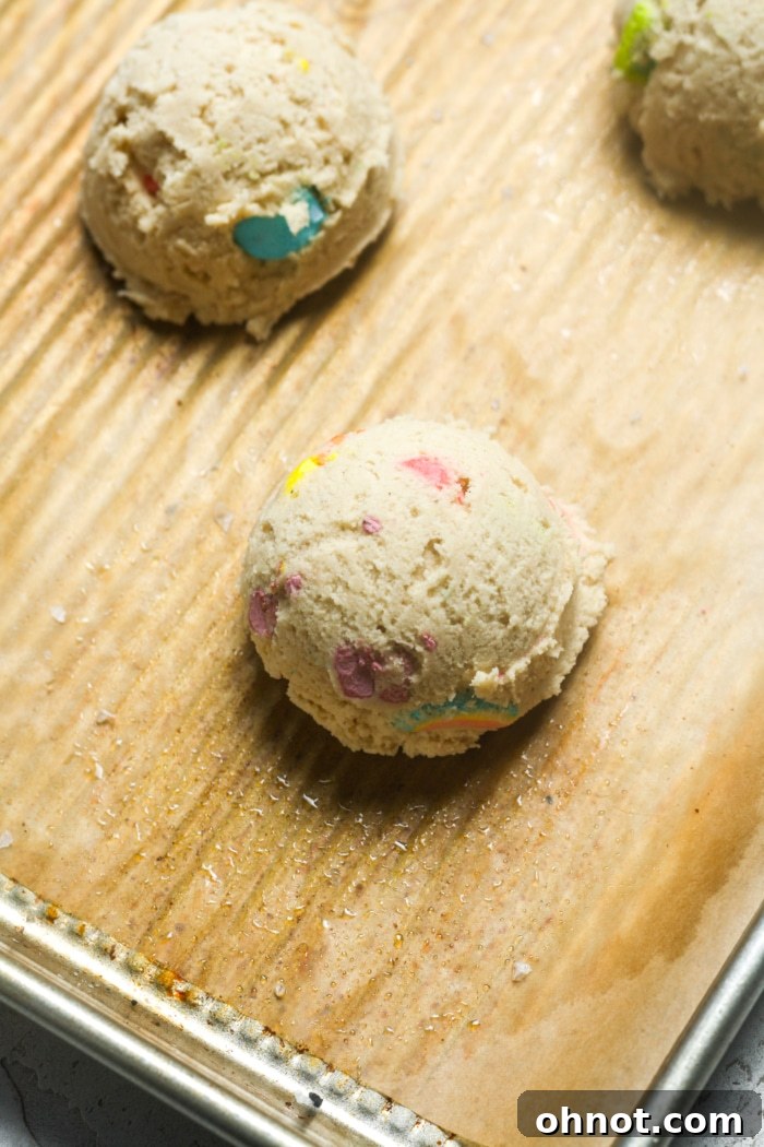 Scooped cookie dough balls placed on a parchment-lined baking sheet, ready for the oven.