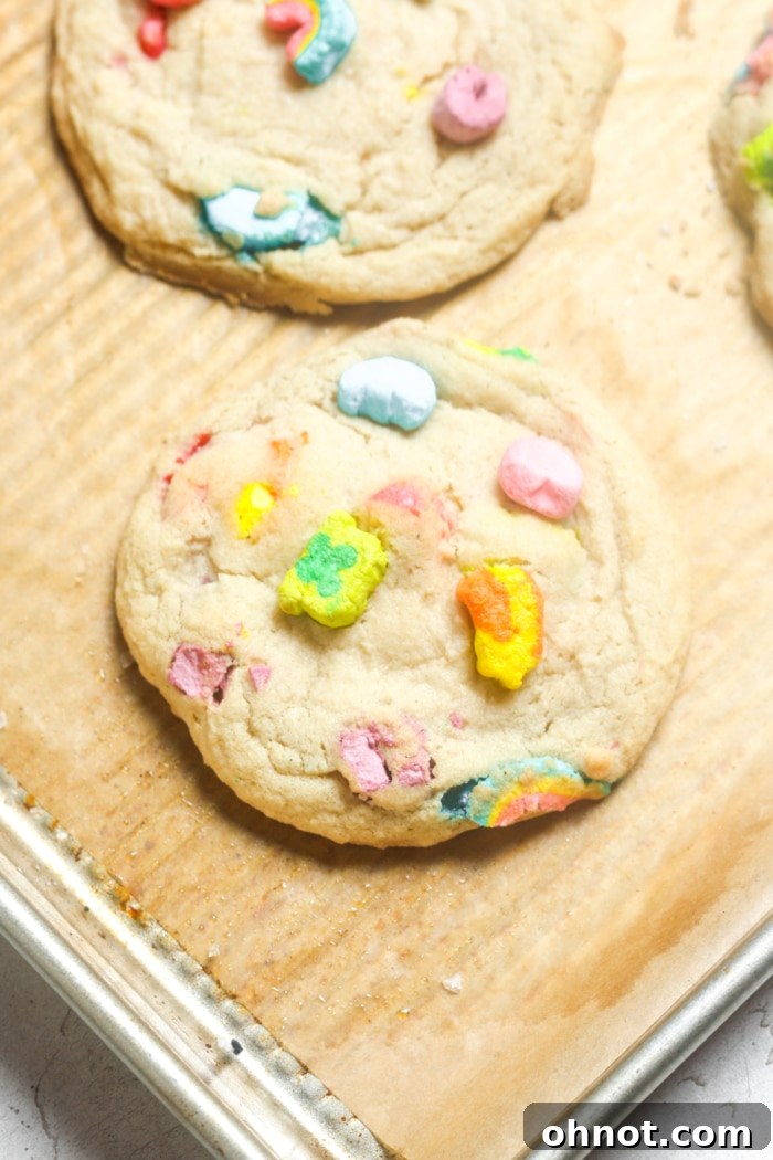 A batch of baked Lucky Charms cookies, fresh from the oven with slightly melted, colorful marshmallows.