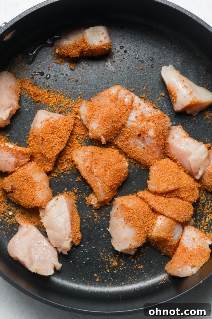 Seasoned chicken sizzling in a hot skillet, perfectly browning.