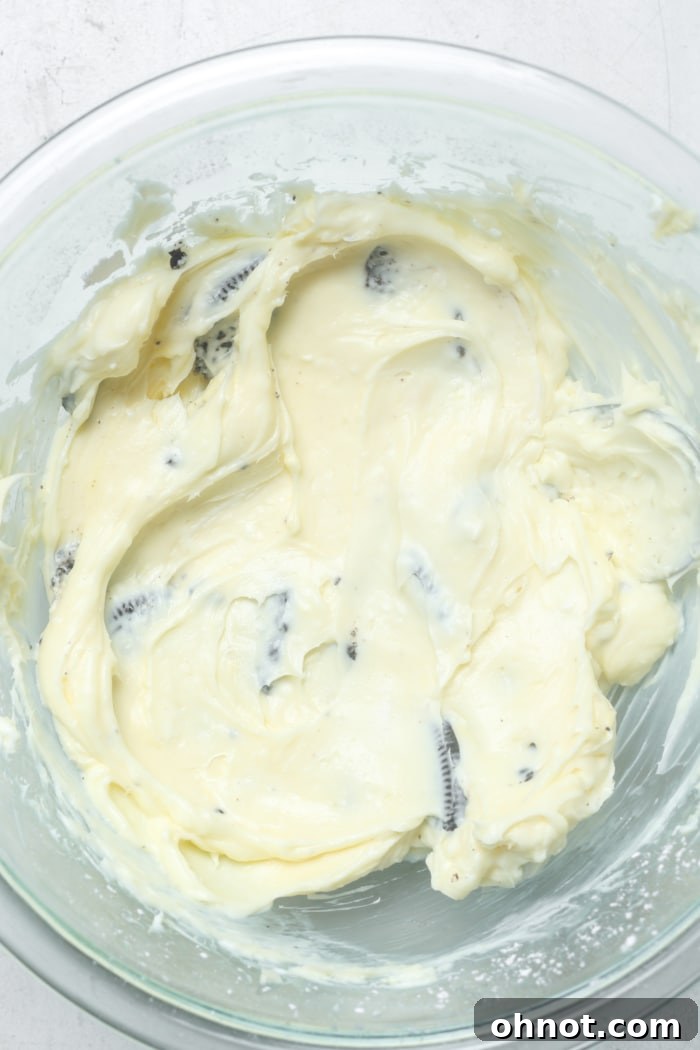 Close-up of a creamy Oreo cheesecake dip with visible chunks of Oreo cookies in a glass bowl.