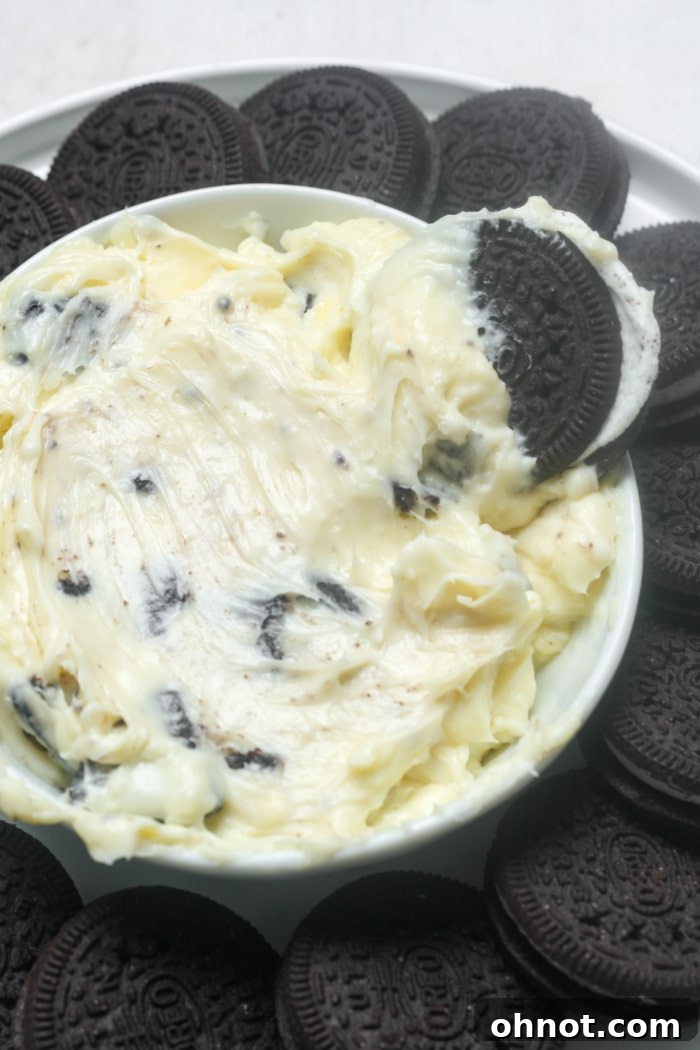 A bowl of creamy cookie dip, garnished with a whole Oreo and some crumbs, ready for serving.